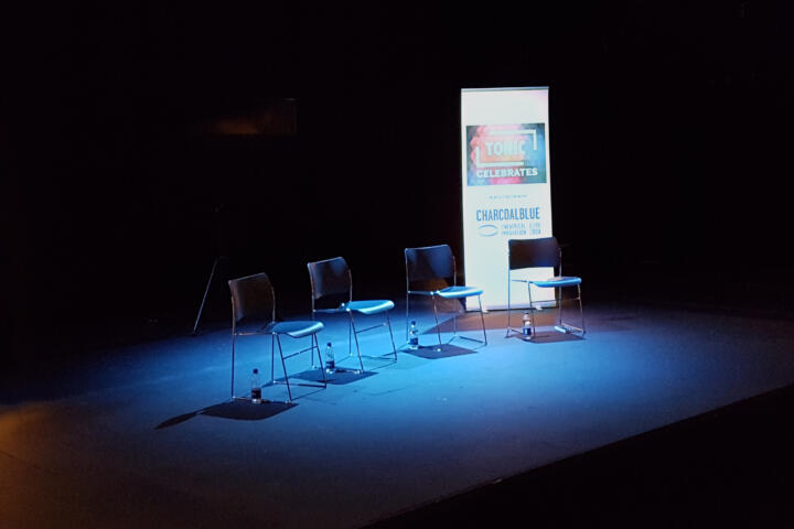 four empty seats on a lit stage