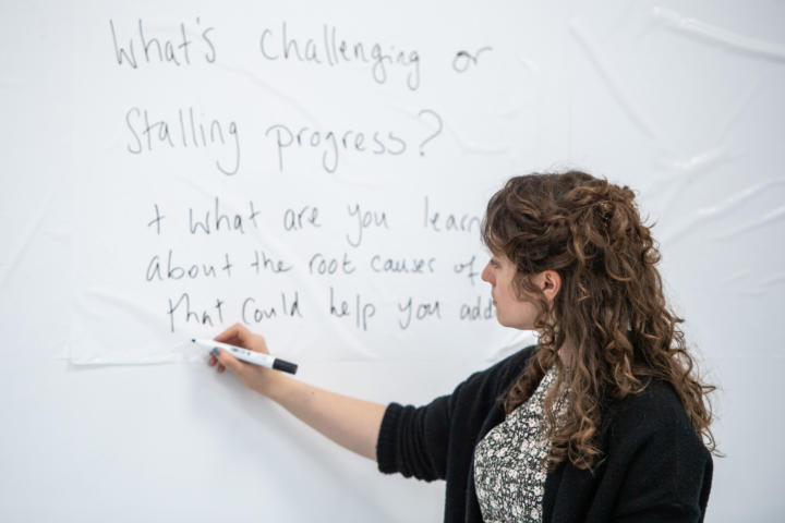 workshop participant writes on a whiteboard